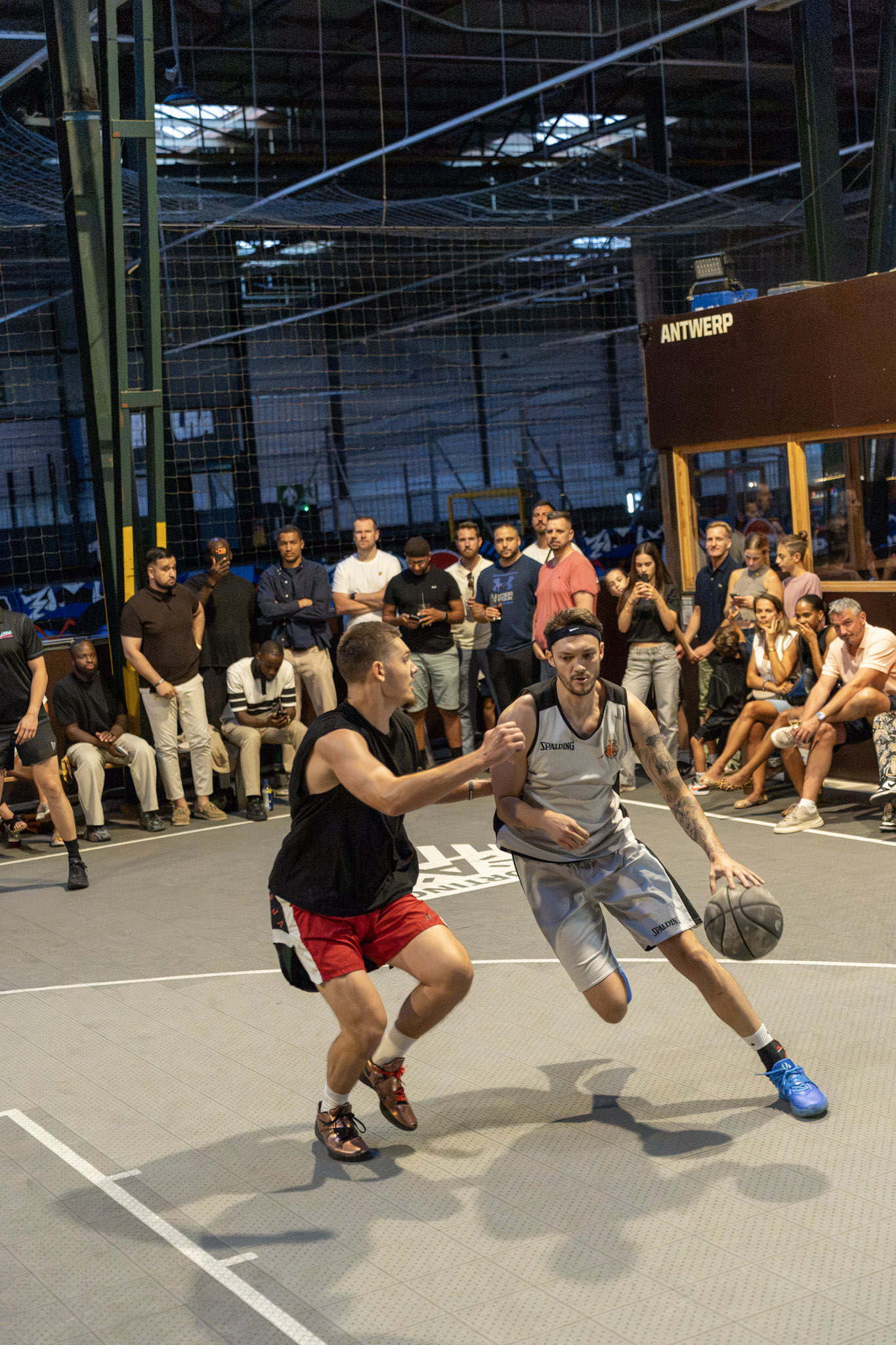 Players facing off during a crowded 1v1 basketball event